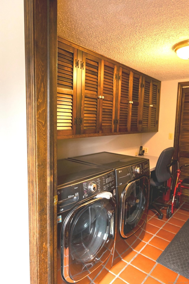 laundry room with tile patterned flooring, washer and dryer, cabinets, and a textured ceiling