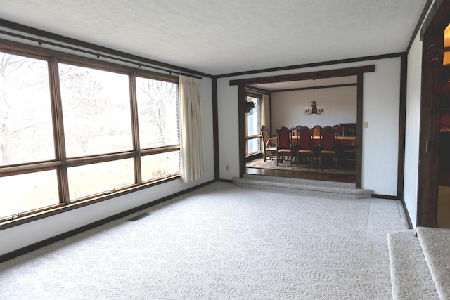 unfurnished living room with a healthy amount of sunlight, ornamental molding, and a textured ceiling