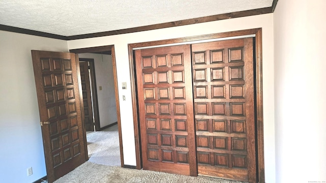 interior space with a textured ceiling, carpet floors, and crown molding