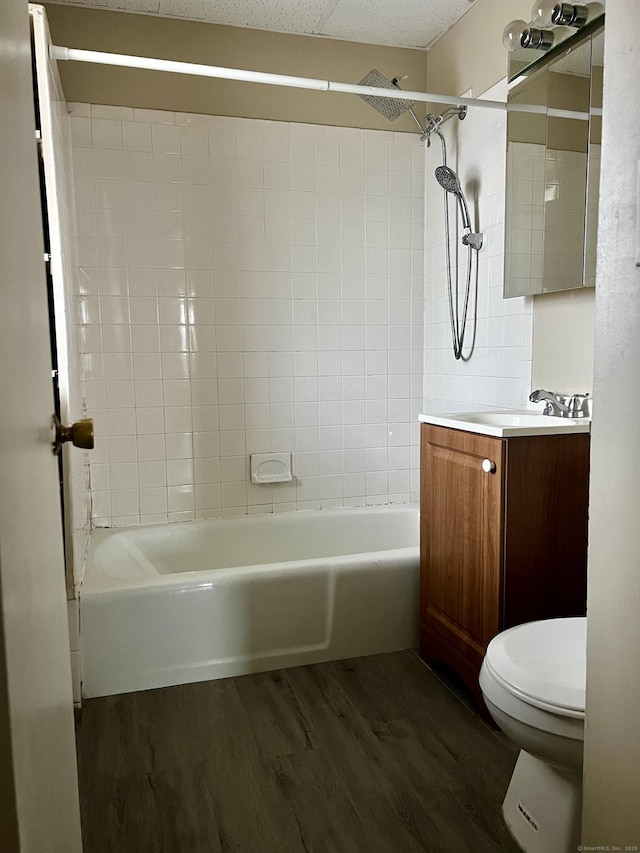 full bathroom featuring hardwood / wood-style flooring, tiled shower / bath, vanity, and toilet