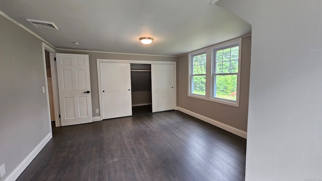 unfurnished bedroom featuring ornamental molding, a closet, and dark hardwood / wood-style flooring