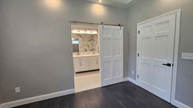107 N Hollow Rd, Hartland, CT 06027 - unfurnished bedroom featuring a barn door, dark wood finished floors, baseboards, and a sink