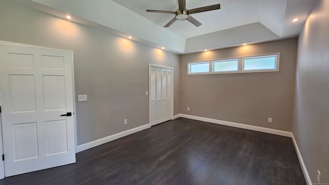 unfurnished room with ceiling fan, a raised ceiling, and dark hardwood / wood-style flooring