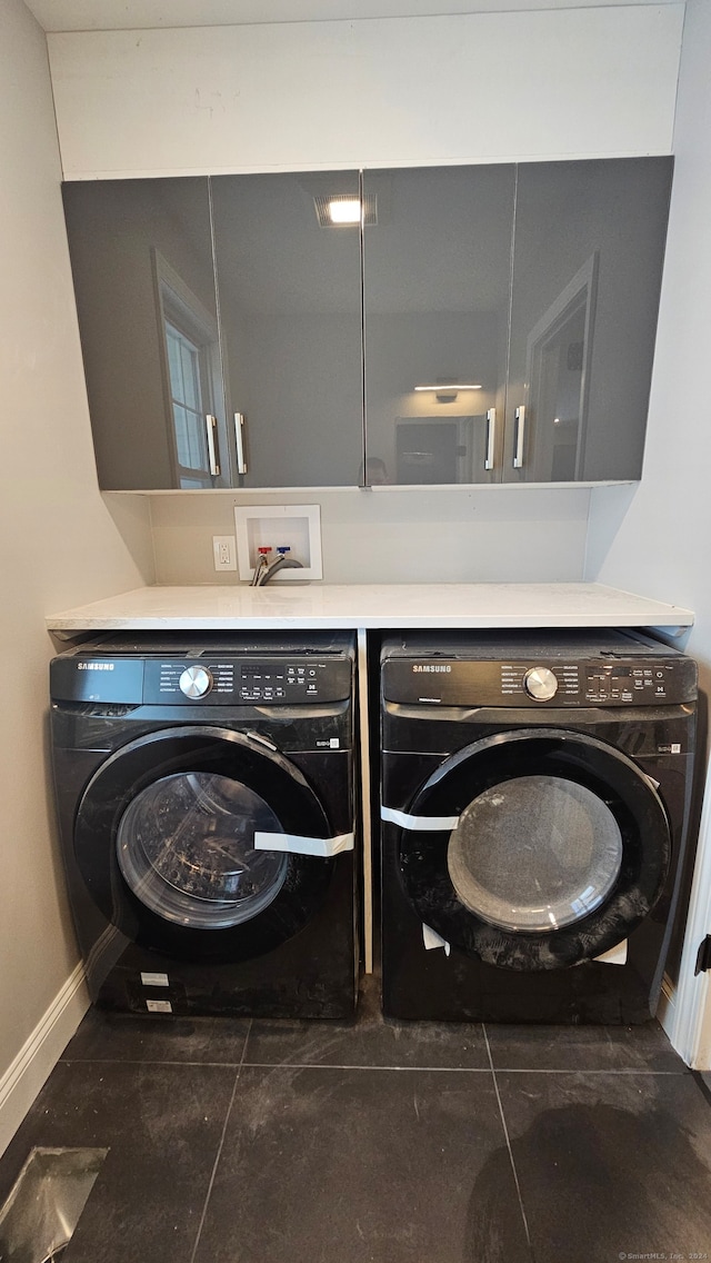 laundry room featuring dark tile patterned floors, cabinets, and washer and clothes dryer