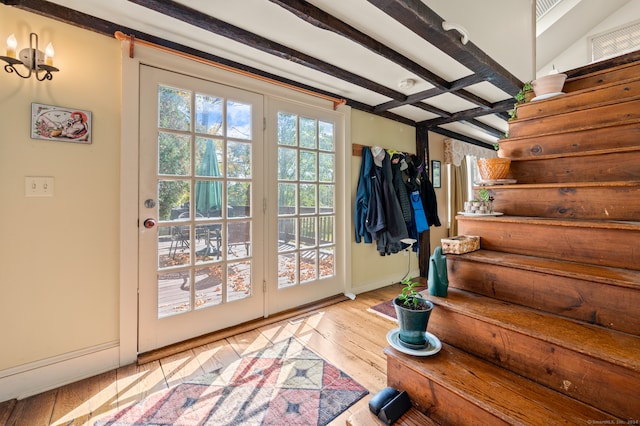 doorway to outside with light wood-type flooring and beamed ceiling