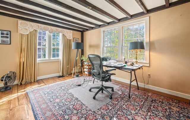 office with light hardwood / wood-style flooring and beam ceiling