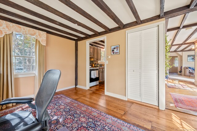 home office with beam ceiling and hardwood / wood-style floors