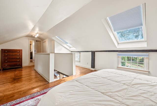 bedroom featuring vaulted ceiling with skylight and light hardwood / wood-style flooring