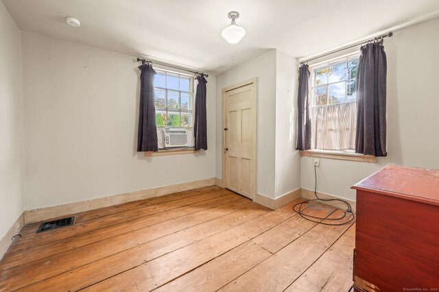 unfurnished bedroom featuring cooling unit and light hardwood / wood-style floors