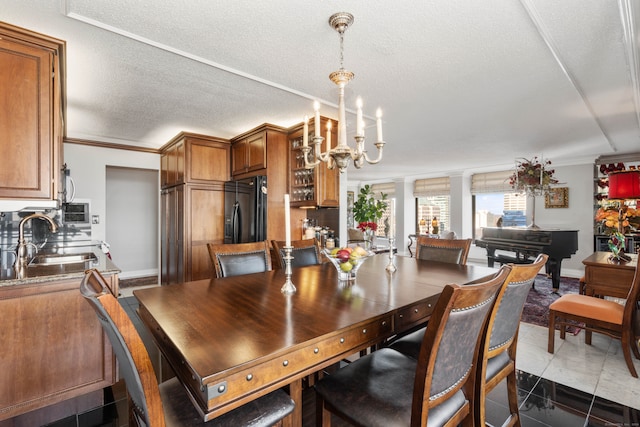 dining room with a textured ceiling, dark tile patterned floors, crown molding, and sink