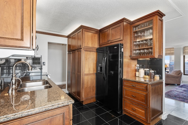 kitchen with sink, crown molding, black fridge, and light stone counters