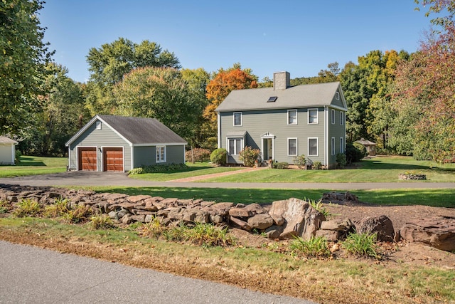 colonial-style house with an outbuilding, a front yard, and a garage