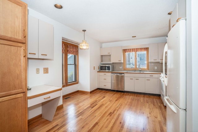 kitchen featuring light hardwood / wood-style flooring, white cabinets, decorative light fixtures, and appliances with stainless steel finishes