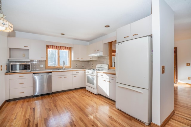 kitchen featuring sink, appliances with stainless steel finishes, tasteful backsplash, light hardwood / wood-style floors, and white cabinetry