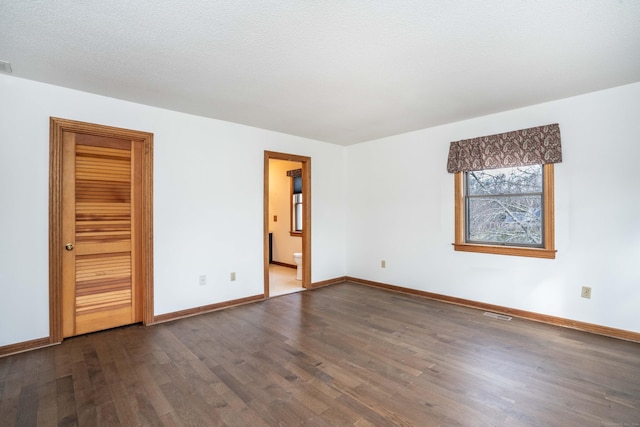 spare room with a textured ceiling and dark wood-type flooring