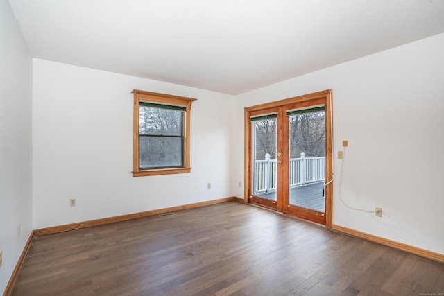 empty room featuring a healthy amount of sunlight and dark hardwood / wood-style flooring