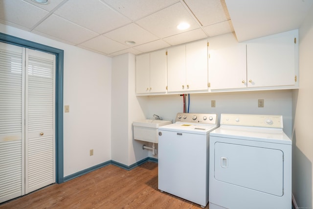 laundry area with separate washer and dryer, sink, cabinets, and light wood-type flooring