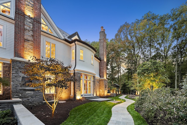 view of side of home featuring stone siding and a chimney