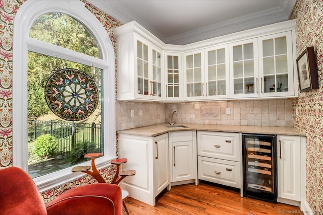 bar featuring light stone counters, white cabinetry, light hardwood / wood-style flooring, ornamental molding, and wine cooler