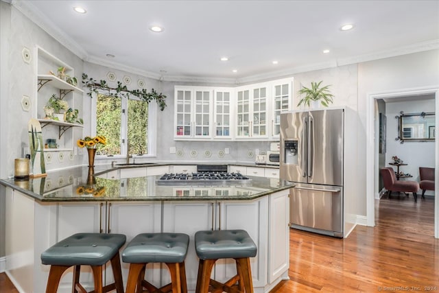 kitchen featuring white cabinets, kitchen peninsula, dark stone counters, light hardwood / wood-style flooring, and appliances with stainless steel finishes