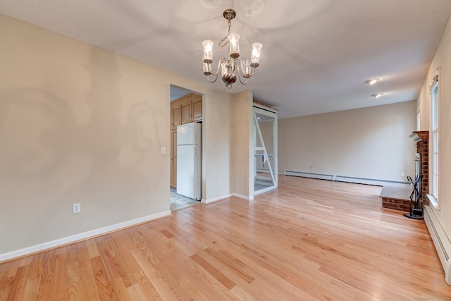 interior space featuring baseboard heating, an inviting chandelier, a fireplace, and light hardwood / wood-style floors