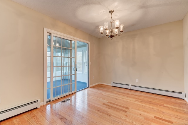 empty room featuring light hardwood / wood-style flooring, a notable chandelier, a textured ceiling, and a baseboard heating unit