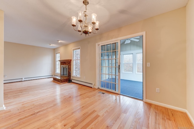 unfurnished living room with light hardwood / wood-style floors, a healthy amount of sunlight, and a baseboard heating unit