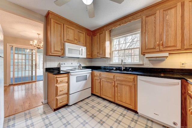 kitchen with backsplash, ceiling fan with notable chandelier, light hardwood / wood-style floors, sink, and white appliances