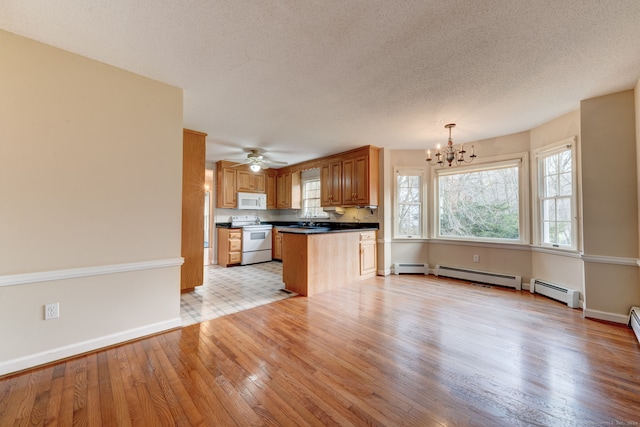 kitchen featuring baseboard heating, light hardwood / wood-style flooring, sink, pendant lighting, and white appliances