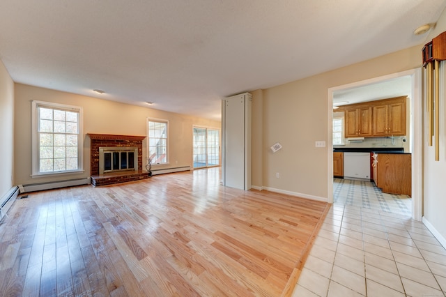 unfurnished living room with light wood-type flooring, baseboard heating, and a fireplace