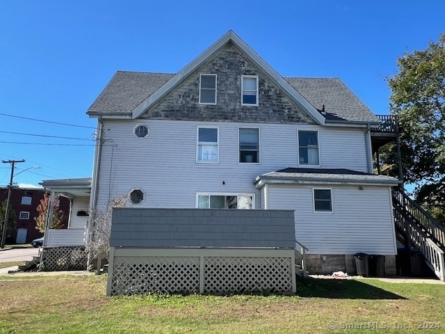 rear view of house with a wooden deck and a lawn