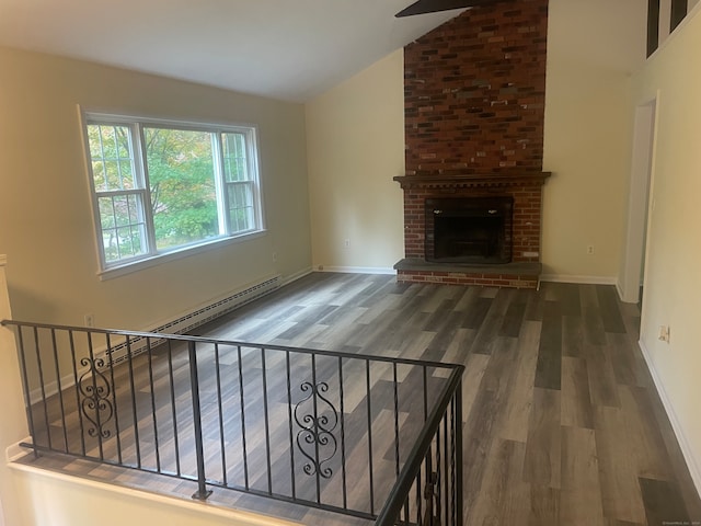 unfurnished living room featuring lofted ceiling, a brick fireplace, baseboard heating, and hardwood / wood-style floors