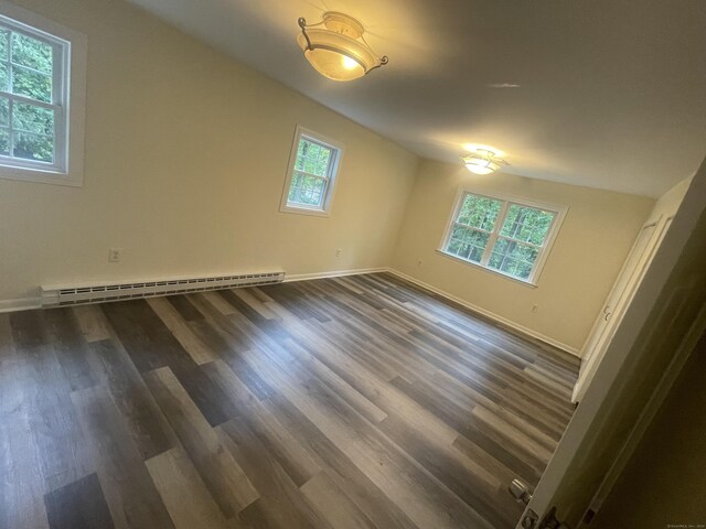 spare room featuring dark hardwood / wood-style flooring, vaulted ceiling, and baseboard heating