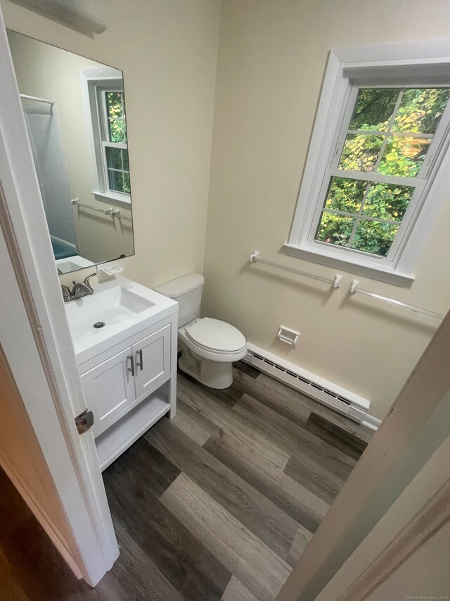 bathroom featuring plenty of natural light, a baseboard heating unit, vanity, and toilet