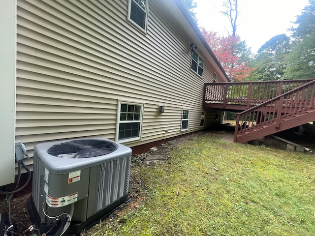 view of property exterior with cooling unit, a yard, and a wooden deck