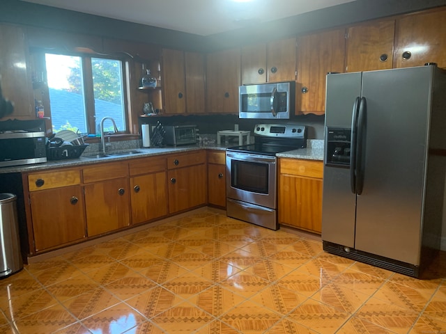 kitchen featuring dark stone counters, appliances with stainless steel finishes, and sink