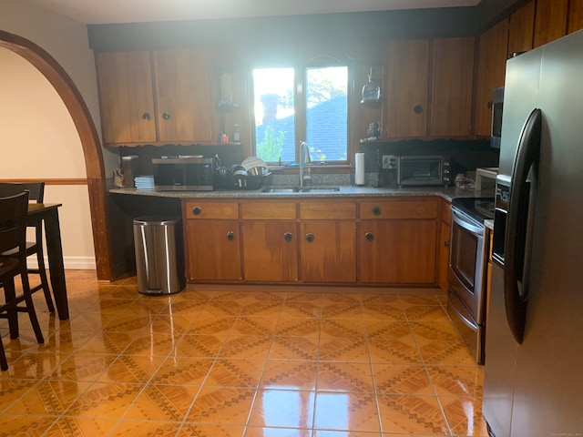 kitchen with appliances with stainless steel finishes, sink, and light tile patterned flooring