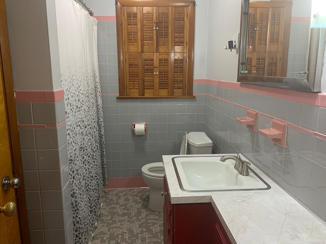 bathroom featuring vanity, tile walls, and toilet