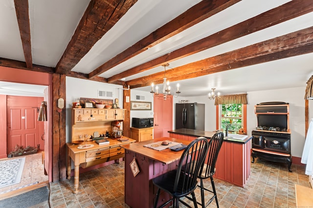 kitchen with hanging light fixtures, beam ceiling, a kitchen island, black appliances, and a notable chandelier