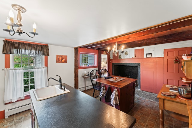 kitchen with hanging light fixtures, a kitchen island with sink, sink, and a baseboard radiator