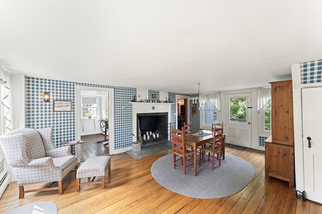 dining area featuring wallpapered walls, plenty of natural light, a fireplace, and hardwood / wood-style floors
