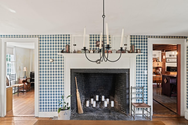 room details with a fireplace, wallpapered walls, and wood finished floors