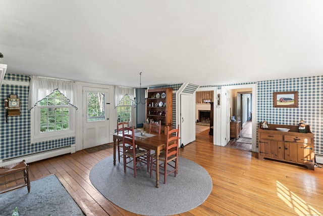 dining room featuring baseboard heating, hardwood / wood-style floors, and wallpapered walls