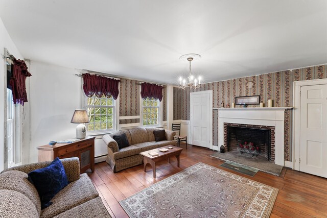 living area featuring hardwood / wood-style floors, a fireplace, a chandelier, baseboard heating, and wallpapered walls