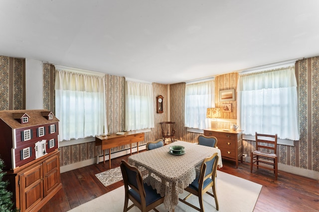 dining room with wallpapered walls, baseboards, baseboard heating, and hardwood / wood-style flooring