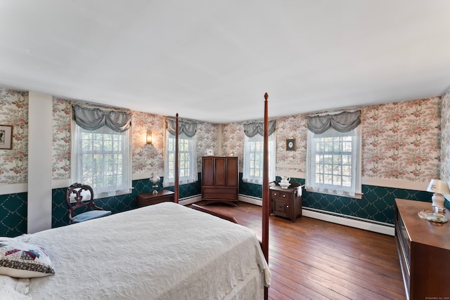 bedroom featuring multiple windows, dark wood-type flooring, and a baseboard heating unit