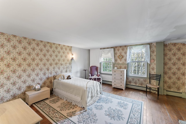 bedroom with wallpapered walls, a baseboard heating unit, and hardwood / wood-style floors