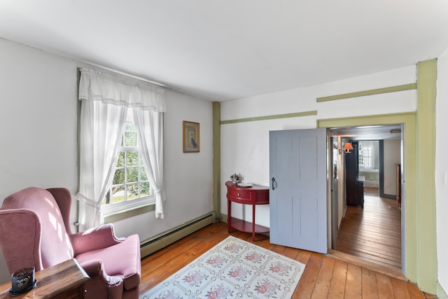 sitting room with a baseboard heating unit and light hardwood / wood-style flooring