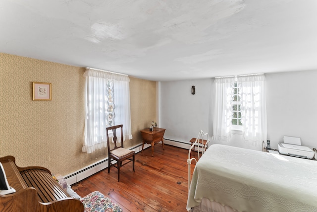 bedroom featuring a baseboard heating unit and wood-type flooring