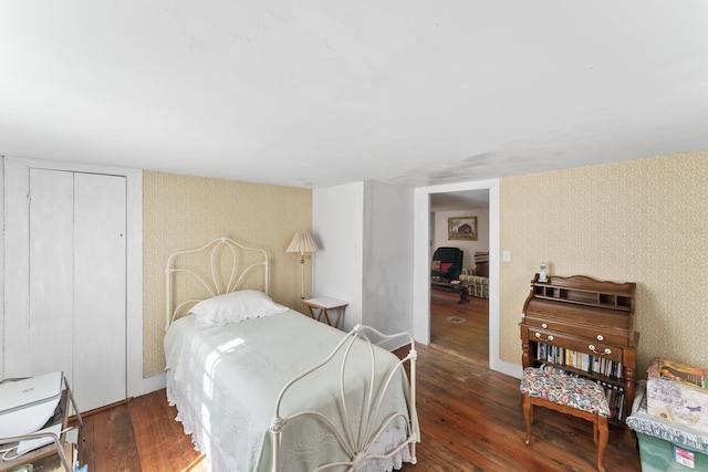 bedroom featuring wallpapered walls, a closet, and hardwood / wood-style flooring